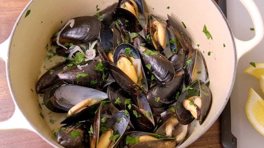 Pot of cooked muscles with herbs and red onions
